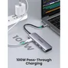 A UGREEN USB-C hub is connected to a laptop, with a power adapter and extension cord in the background. Text highlights '100W Pass-Through Charging'. Produktbild-Vorschau