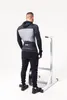 A man wearing a weightlifting belt and athletic clothing stands next to a weightlifting rack. Náhľad obrázku produktu