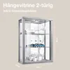 A glass display cabinet with shelves, containing decorative items like toy cars and tableware. Dimensions are indicated. Produktbild-Vorschau
