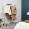 A clothing rack with several coats and a sweater, a purse hanging on the side, in a bedroom. The rack is on wheels. Podgląd zdjęcia produktu