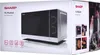 The image shows the packaging of a SHARP microwave oven. The front of the box displays a large image of the microwave, along with several feature icons and text. The right side of the box shows a lifestyle image of a couple in a kitchen, along with smaller Voir les images du produit