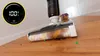 A floor cleaning device is shown in action on a wooden floor, with a digital display indicating 100% charge. Produktbild-Vorschau