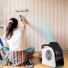 A person is painting a wall while a floor fan is blowing air. Voir les images du produit