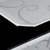 Close-up view of the edge of a white shelf with gray scrollwork pattern, sitting above a black surface. Produktbild-Vorschau