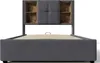 A front view of a gray upholstered bed frame with a headboard featuring built-in shelving. Náhľad obrázku produktu