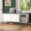A white shoe bench with a gray cushion is placed in a hallway next to a window. The bench has two sliding doors with arched panels and an open compartment on the right side containing shoes and a basket. A decorative pillow rests on the cushion, and a fram Produktbild-Vorschau