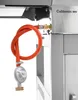 A close-up view of a gas regulator and hose attached to a barbecue grill. Náhled obrázku produktu