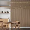 A dining room setting with wooden wall panels, a round wooden table, and chairs. Produktbild-Vorschau