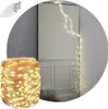A coil of warm white LED string lights is shown in the foreground, with a strand of the lights cascading down in front of a mirror in the background. Produktbild-Vorschau