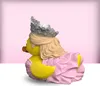 A 3D render of a Glinda the Good Witch inspired rubber duck toy, wearing a crown and a pink ruffled dress, set against a soft pink gradient background. Náhled obrázku produktu