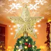 A golden star-shaped Christmas tree topper with LED lights is shown projecting snowflake patterns onto a ceiling. Produktbild-Vorschau