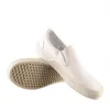 A pair of white Vans slip-on shoes are shown against a white background. One shoe is placed on top of the other, with the sole of the bottom shoe visible. Produktbild-Vorschau