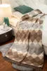 A blanket is draped over a bed next to a nightstand with a lamp. Produktbild-Vorschau