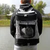 A person wearing a backpack with a dog inside, standing near a body of water. Produktbild-Vorschau