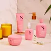 A collection of pink hair care products arranged on a light-colored surface with a marble-patterned background and a lit candle. Produktbild-Vorschau