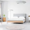 A minimalist bedroom with a bed, floor lamp, and a round rug. Anteprima dell’immagine prodotto