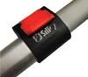 A close-up of a black clamp with a red locking mechanism attached to a silver pole. Náhled obrázku produktu