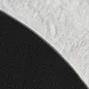 A close-up view of the underside and edge of a round rug, showing the black dotted backing and the white fluffy material. Produktbild-Vorschau