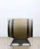 A barrel-shaped object, likely a decanter or decorative item, is displayed on a stand within a clear plastic case. The background is plain white, and the object rests on a wooden surface. Produktbild-Vorschau