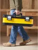 A person is walking and carrying a yellow and black toolbox. Anteprima dell’immagine prodotto