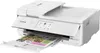A white Canon PIXMA TS9551Ca printer is shown from a slightly elevated front-left angle, with a printed document partially ejected from the paper tray. Podgląd zdjęcia produktu