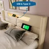 A bed with a headboard featuring integrated LED lighting and USB charging ports, with two phones charging. Produktbild-Vorschau