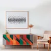 A colorful sideboard with geometric patterns is displayed in a well-lit room, next to a chair and under a framed artwork. Anteprima dell’immagine prodotto
