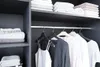 A view inside a modern closet with neatly folded towels on shelves and clothes hanging on a rod. Produktbild-Vorschau