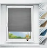 A gray pleated blind is shown covering most of a window, with a small vase of yellow flowers on the windowsill below. To the right, there are swatches of different colored blinds. Produktbild-Vorschau