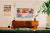 A modern living room with a Samsung Frame TV displaying artwork above a wooden media console. Voir les images du produit