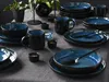 A set of blue and black ceramic dishes arranged on a gray tablecloth. Produktbild-Vorschau