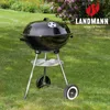 A black charcoal kettle grill is placed on a green lawn with a flowering bush in the background. Náhľad obrázku produktu