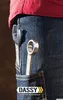 A close-up view of a person's hip and pocket area, showing two wrenches tucked into the pocket and hanging from the waistband of blue denim jeans. The person is wearing a red shirt. Produktbild-Vorschau