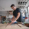 A man is sanding a wooden surface in a workshop. Anteprima dell’immagine prodotto