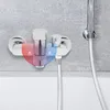 A chrome-finished bathroom faucet with hot and cold water indicators, mounted on a gray tiled wall above a white bathtub. Podgląd zdjęcia produktu