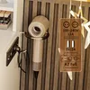 A close-up of a hairdryer holder mounted on a wall with a power adapter and USB ports displayed next to it. Produktbild-Vorschau