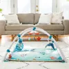 A baby play gym with toys is set up on a rug in a living room, with a sofa and doorway in the background. Produktbild-Vorschau