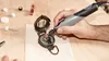 A person is using a Dremel rotary tool to work on an antique-looking compass. Anteprima dell’immagine prodotto