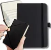 A person's hands are holding a small black notebook, which is being placed into a larger black notebook. The larger notebook is open, showing lined pages. Náhľad obrázku produktu