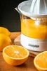 A citrus juicer with oranges and lemons on a wooden surface. Produktbild-Vorschau