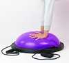 A person's hands and lower legs are visible as they balance on a purple Bosu ball with black resistance bands attached. Náhled obrázku produktu