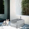 A cat sits next to a litter box on a patio. Produktbild-Vorschau