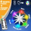 A star-shaped light fixture with multiple colored lights radiating from it, set against a starry night sky background. A remote control is shown in the foreground. Produktbild-Vorschau