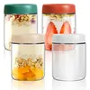 Four glass jars with different colored lids, filled with yogurt and fruit or granola. Produktbild-Vorschau