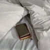A close-up view of bedding with two books and a small purple flower. Produktbild-Vorschau