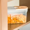 A clear plastic food storage container filled with cornflakes, placed on a shelf. Produktbild-Vorschau