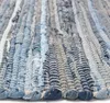 A close-up view of a woven rug made from strips of denim fabric. Náhled obrázku produktu