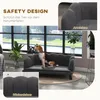 A dog is sitting on a dark gray couch in a room with large windows. Náhled obrázku produktu