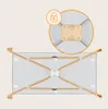 A close-up view of the underside of a baby travel bed, highlighting its folding mechanism and locking feature. Produktbild-Vorschau