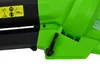 A close-up view of a green and black leaf blower, focusing on a lever and warning labels. Podgląd zdjęcia produktu